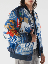 Man wearing a multicolor Dodgers Champions print bomber jacket with ribbed hem, unzipped over a white tee