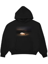 Black fleece hoodie with a sunset beach photo of a woman in white lying on the sand with a red balloon, and a front kangaroo pocket