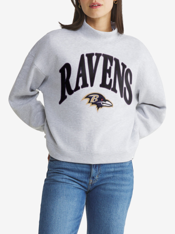 Woman wearing heather gray Baltimore Ravens mock neck pullover sweatshirt with arched black RAVENS wordmark and Ravens bird head logo on the front