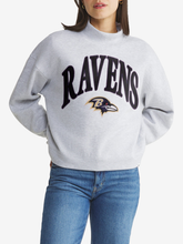 Woman wearing heather gray Baltimore Ravens mock neck pullover sweatshirt with arched black RAVENS wordmark and Ravens bird head logo on the front