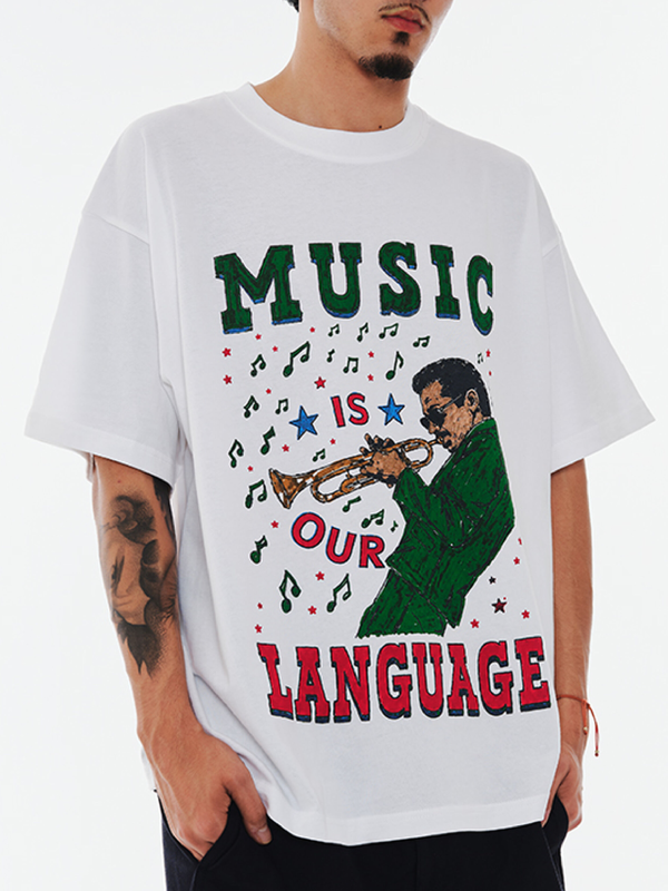 Model wearing white Bueno Music Is Our Language oversized tee with trumpet player graphic and colorful music notes