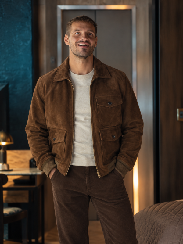 Tyler Conti wearing the chestnut brown suede jacket from The Gentlemen season 2, styled with a cream sweater