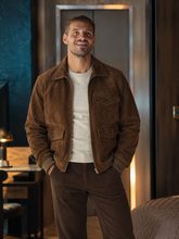 Tyler Conti wearing the chestnut brown suede jacket from The Gentlemen season 2, styled with a cream sweater