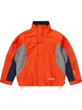 Orange Supreme Gore-Tex jacket with hood down and collar zipped up, highlighting the colorblock paneling.