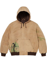 Front view of the tan hooded jacket with hood up, showing the cropped graphic on the pocket area.