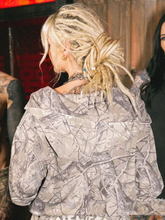 Back view close-up of model wearing treecamo zip-up hoodie showing hood and fabric texture